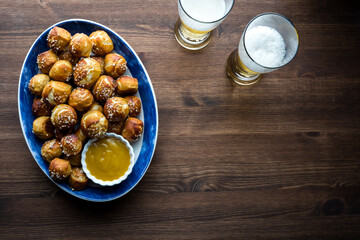 Top down view of a platter of pretzel bites served with mustard sauce and beer.