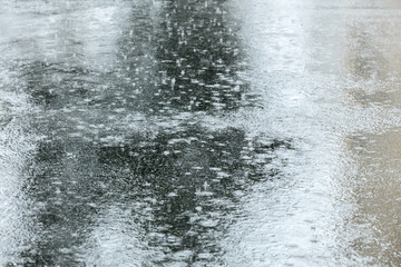 flooded city sidewalk with raindrops falling in puddles