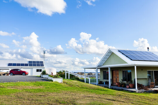 Sustainable off grid living with solar panels on house and shed roof, electric car and wind turbine