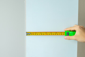 Man hand using tape measure for measuring furniture at home. DIY, Interior design, repairing and improvement home or apartment concepts