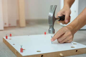 man using hammer hammering a nail into wooden boards, assembling or repairing furniture at home. DIY, Renovation, repairing and development home or apartment concepts