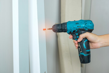 man using a cordless screwdriver assembling furniture at home, Carpenter working with electric screwdriver on the work