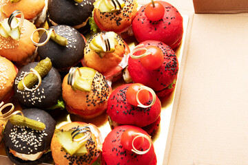 Small burgers on dark background.