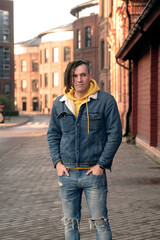 Handsome man with dreadlocks posing on city street. Positive male looking away, smiling.