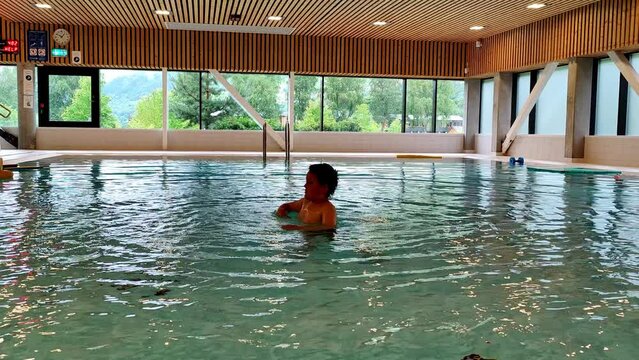 Boy with autism playing and flapping hands alone in swimming pool - Static clip showing boy having fun and doing weird hand movements