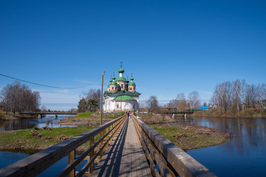 View of the Cathedral of the Smolensk Icon of the Mother of God and the old wooden bridge on the Megrega river on a sunny. Olonets, Karelia