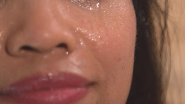 CLOSE UP: Sweat drops dripping down the beautiful face of a young woman in sauna. Detailed view of lady's face sweating in Finnish sauna for detoxification and strengthening of the immune system.