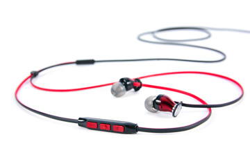 In ear headphones speaker button control isolated on white background. Closeup red and black wire in-ear headphones speaker button volume control isolated.