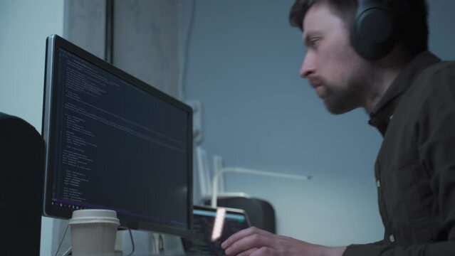 Caucasian man in headphones IT coder programmer software engineer use laptop computer typing code develop program programming java language application on screen web system app development concept.