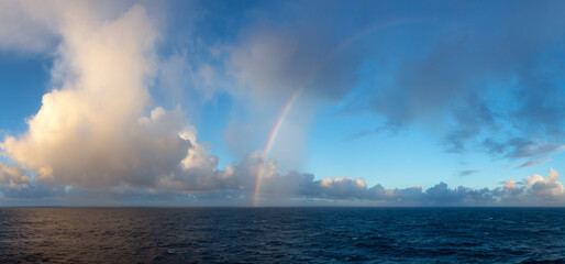 Dramatic Colorful Sunrise Sky over North Atlantic Ocean with Rainbow. Cloudscape Nature Background. Panorama
