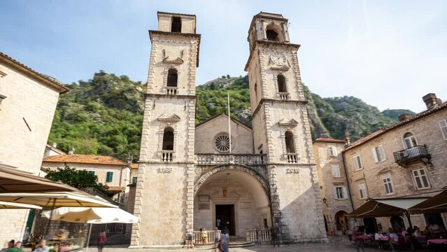 Kotor Montenegro cathedral hyper-lapse: time-lapse of catholic Christian stone church of Saint Tryphon, with bell towers, on a small square in old historical town and famous tourist destination. 