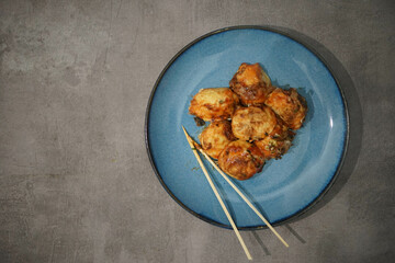 traditional japanese food, takoyaki with sauce on blue plate on concrete background