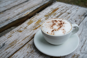 Hot cappuccino in white cup with wooden background,coffee is a popular drink all over the world.