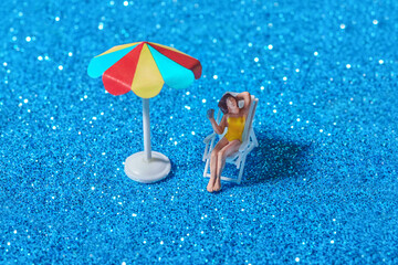 Toy woman relaxing under beach umbrella