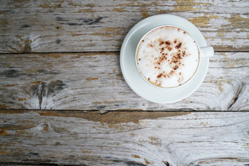 Hot cappuccino in white cup with wooden background,coffee is a popular drink all over the world.