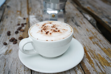 Hot cappuccino in white cup with wooden background,coffee is a popular drink all over the world.