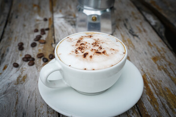 Hot cappuccino in white cup with wooden background,coffee is a popular drink all over the world.