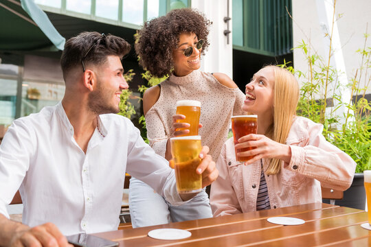 Cheerful multiethnic friends cheering in outdoor pub