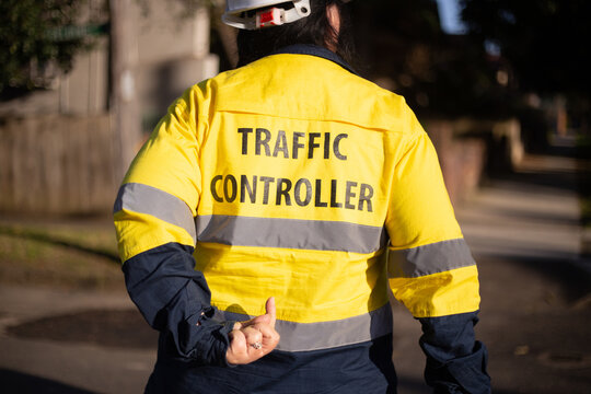 Back shot of a traffic controller wearing yellow jacket with silver reflectors