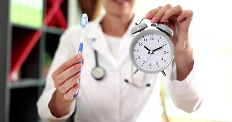 Dentist is working in dental hospital holding an alarm clock and toothbrush