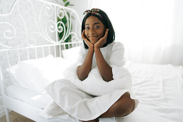 Beautiful young thoughtful african woman sitting in morning bed