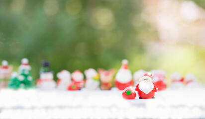 santa doll and presents with snow decorated  background blurred group of santa claus dolls. concept christmas celebration, santa claus deliver presents to children