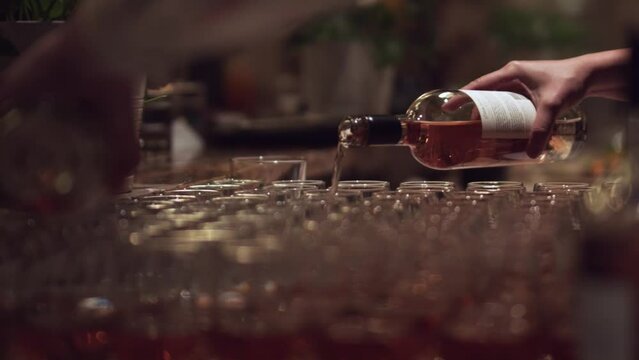 Low side shot of pouring rose wine to the glasses at the wedding event