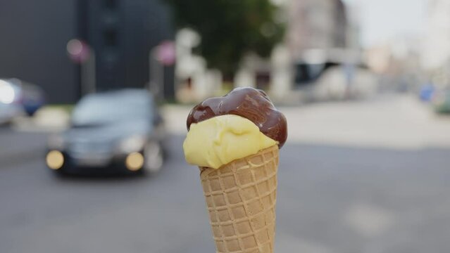 Focused close-up of a vanilla and chocolate ice cream cone being spun by a person on the street