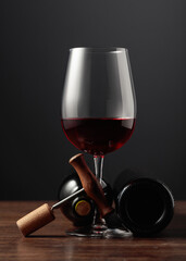 Red wine and corkscrew on a wooden table.