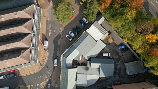 Straight down birds eye drone view of  industrial units, busy roads, cars and carparks.