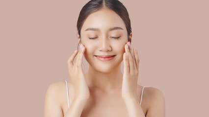 Face cream commercial advertising concept. Young beautiful Asian woman massages her face gently...
