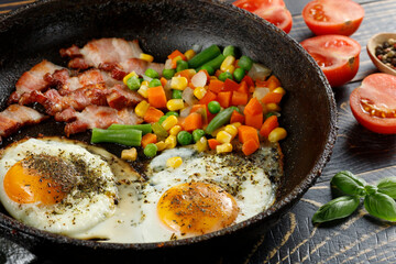 Fried eggs with vegetables in a pan.
