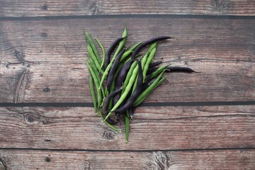 green and purple beans on wooden background