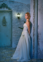 bright girl with a fashionable hairstyle in a white dress in an entourage studio