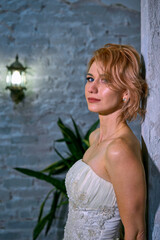 bright girl with a fashionable hairstyle in a white dress in an entourage studio