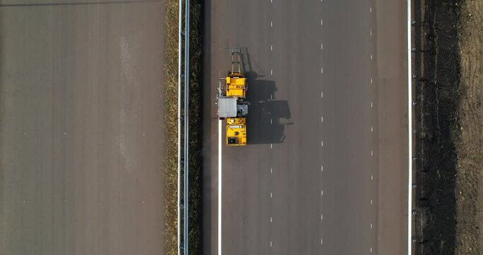 Drawing solid markings on a new road. Application of road markings by marking machine, aerial view. The concept of road construction. Solid line. 
