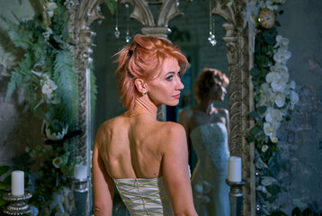 bright girl with a fashionable hairstyle in a white dress in an entourage studio