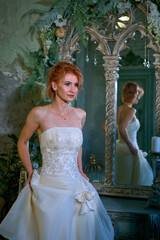 bright girl with a fashionable hairstyle in a white dress in an entourage studio