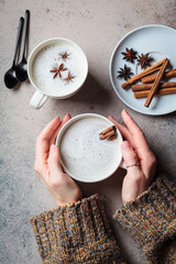 Homemade chai latte with cinnamon and star anise in white cup, dark background.