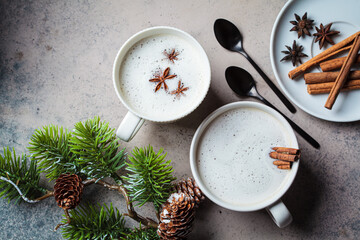Homemade chai latte with cinnamon and star anise in white cup, dark background. Christmas...