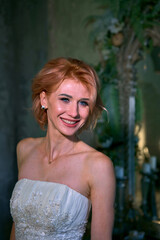 bright girl with a fashionable hairstyle in a white dress in an entourage studio
