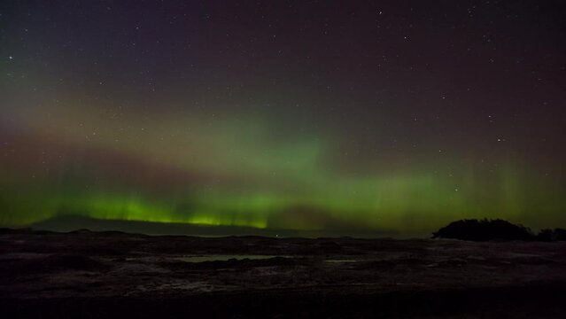 Time-lapse of the northern lights (aurora borealis) dancing in the night sky above lake ice on the shore of Lake Superior.  Shot near Marquette, Michigan in 4K