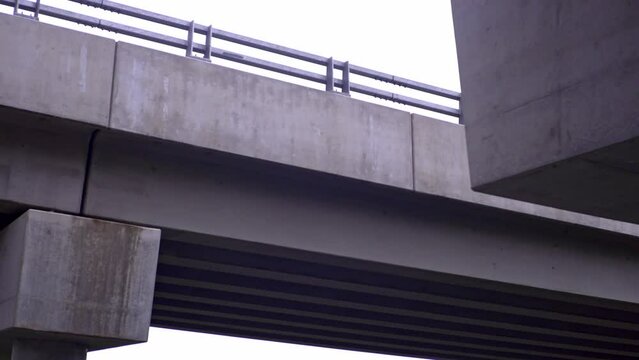 Camera pans down from overpass and across to reveal a road and mountains in the background on a gloomy day