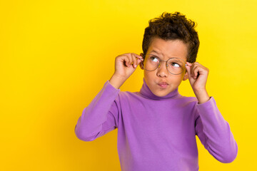 Portrait of minded pensive person arms touch eyewear look empty space isolated on yellow color background