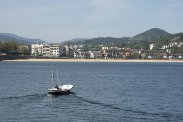 Fototapeta na wymiar Boat sailing in the bay of La Concha, city of Donostia - San Sebastian, Euskadi