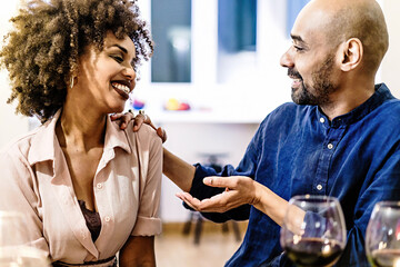 Happy couple flirting sitting on a table at home having fun talking together