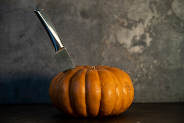 pumpkin with a protruding knife in it on a dark background