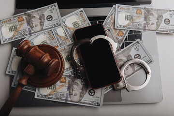 Top view of smartphone with handcuff on a dollar banknotes and laptop. Cyber crime concept