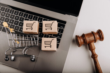 Judge gavel and shopping cart with delivery boxes on a laptop. Online fraud and law