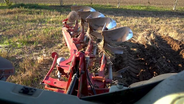 Farmer lowering reversible plow in the ground, plowing soil for seeding